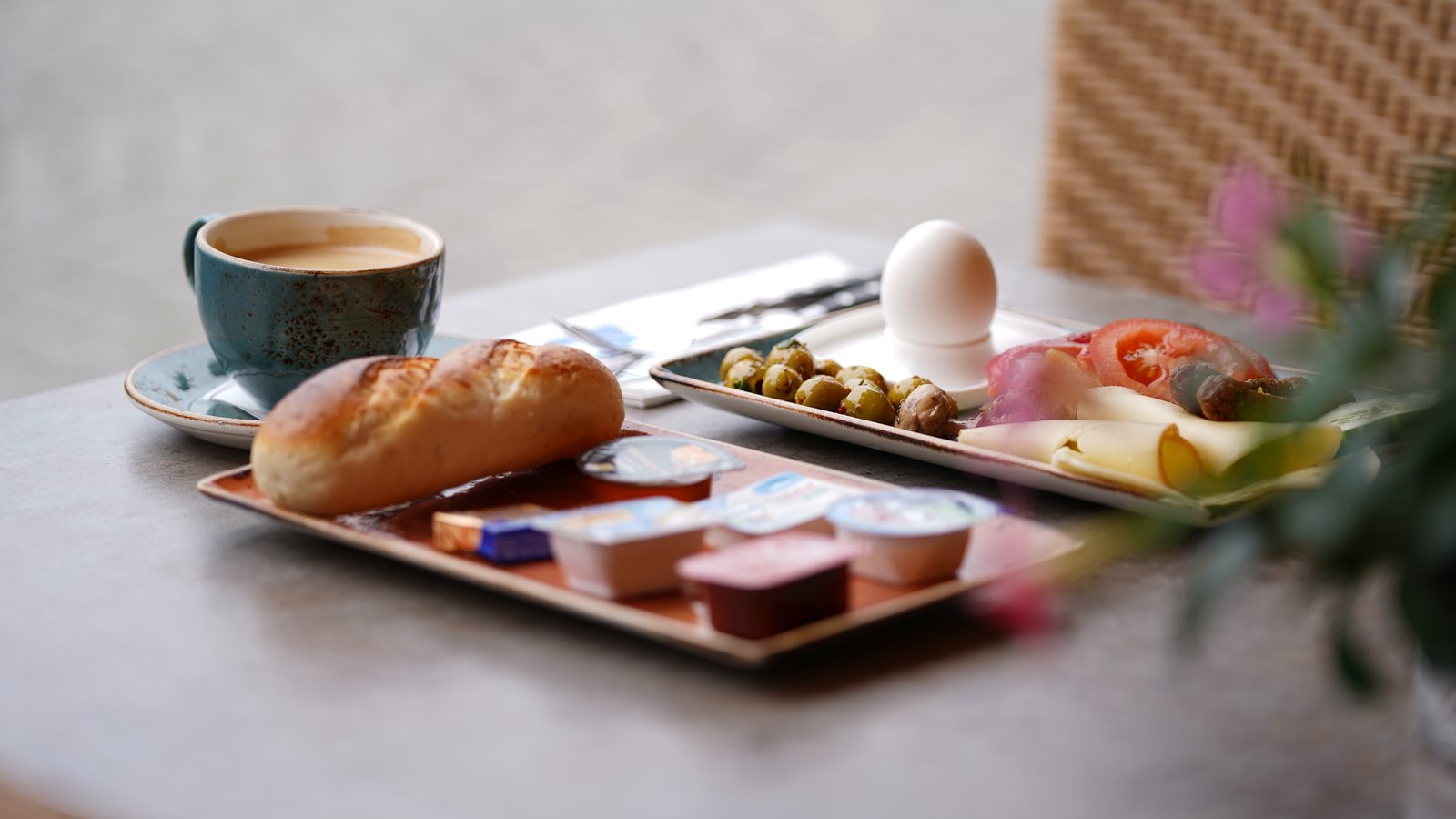 Gedeckter Frühstückstisch mit Kaffee, frischem Brot und Frühstücksteller